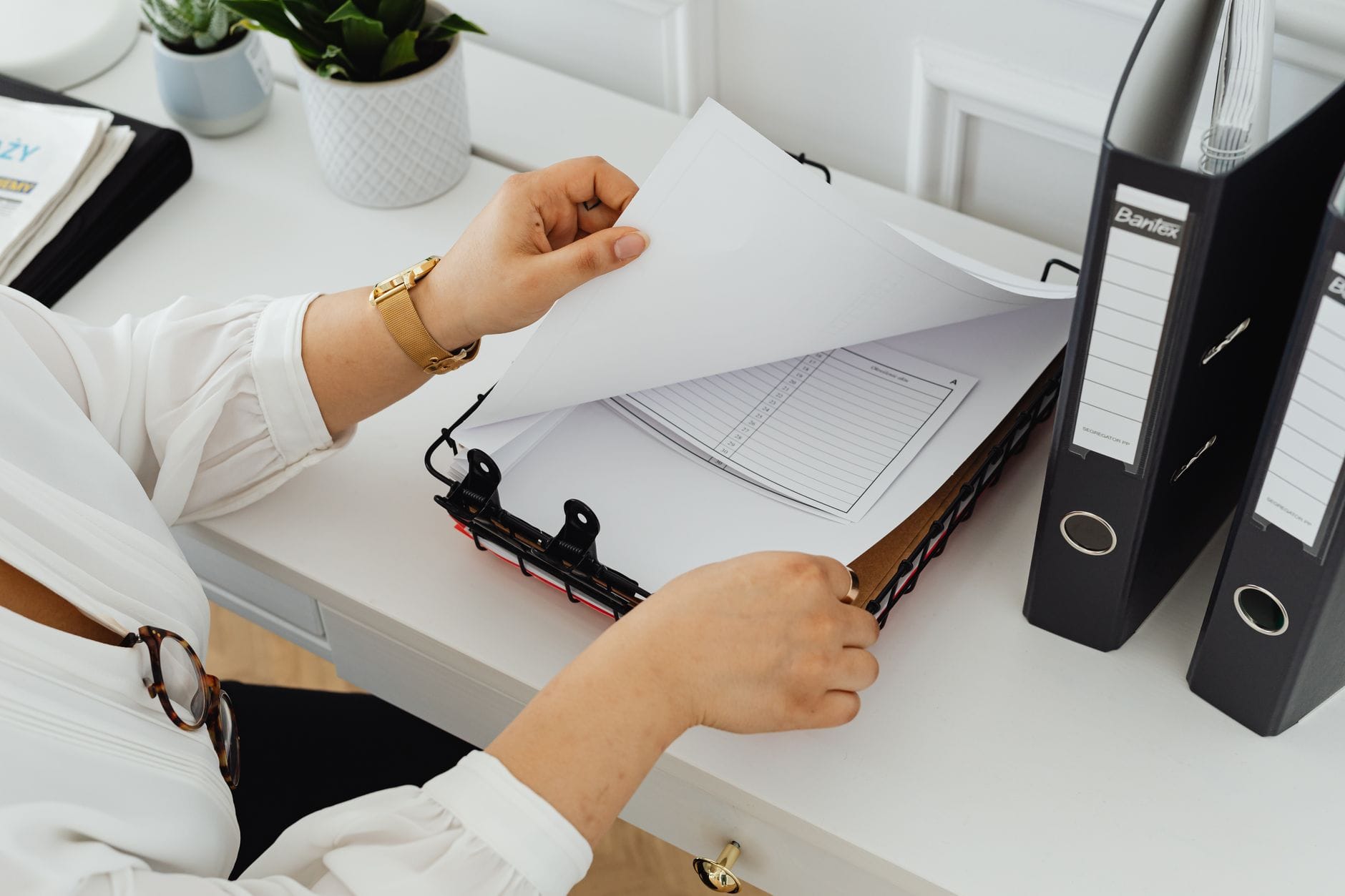 Business professional sorting through documents in a modern office setting.