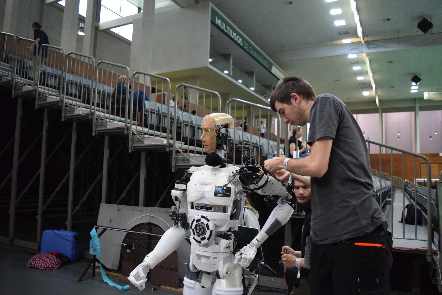 Technician working on humanoid robot at a tech exhibition in Guimaraes, Portugal.