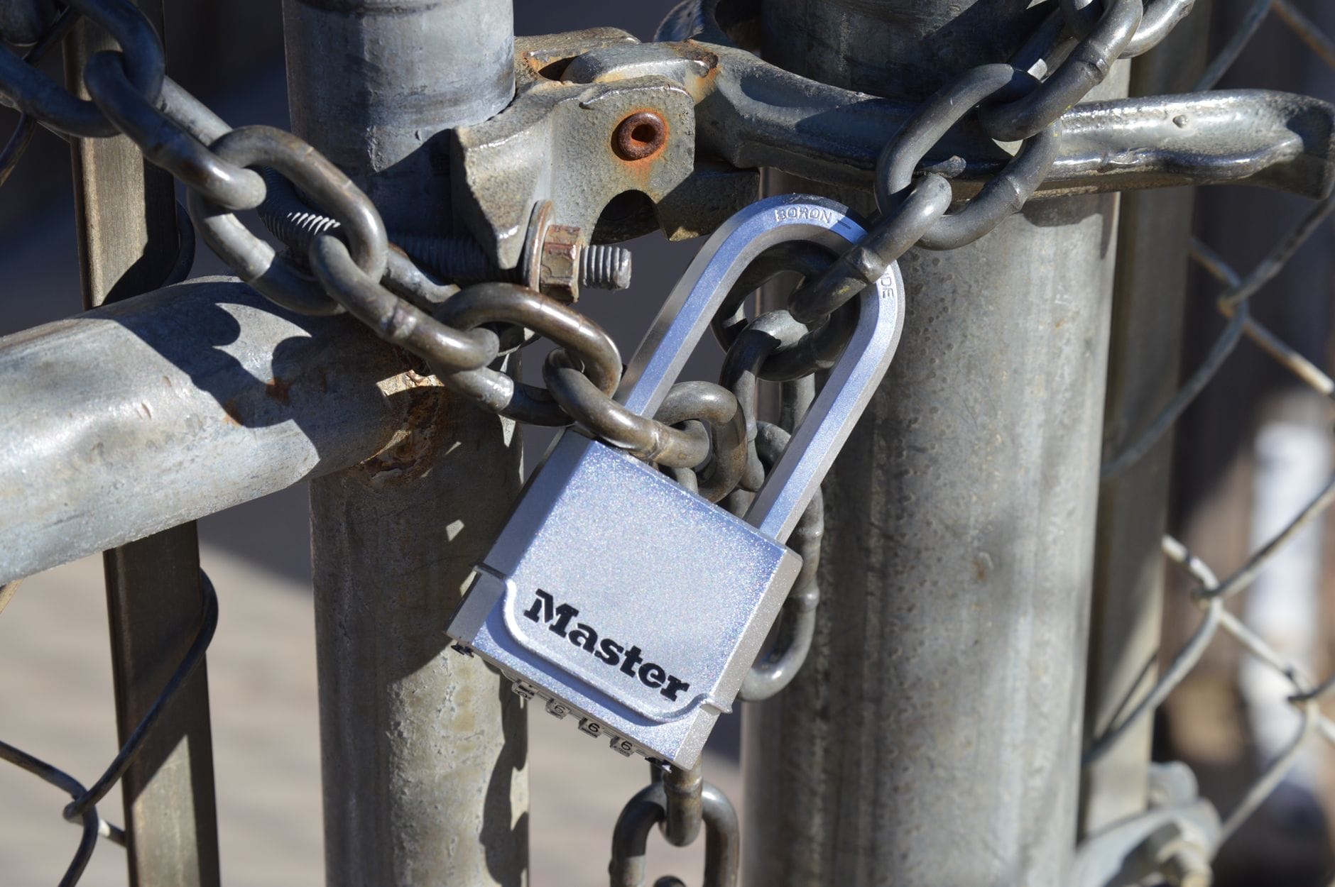 Detailed view of a padlock securing a metal gate with a chain, emphasizing safety and security.